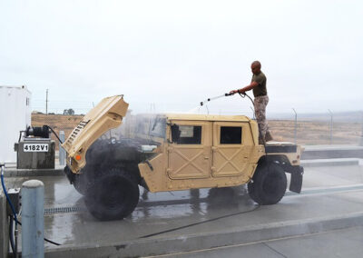 Man in military uniform using in-ground was system pad to wash military vehicles