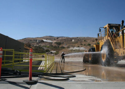 Person using the in-ground wash system pad to wash construction vehicles