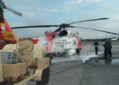 People using the total aircraft washing system to wash a military helicopter
