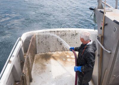 Man using the marine invasive species control wash to wash a commercial boat