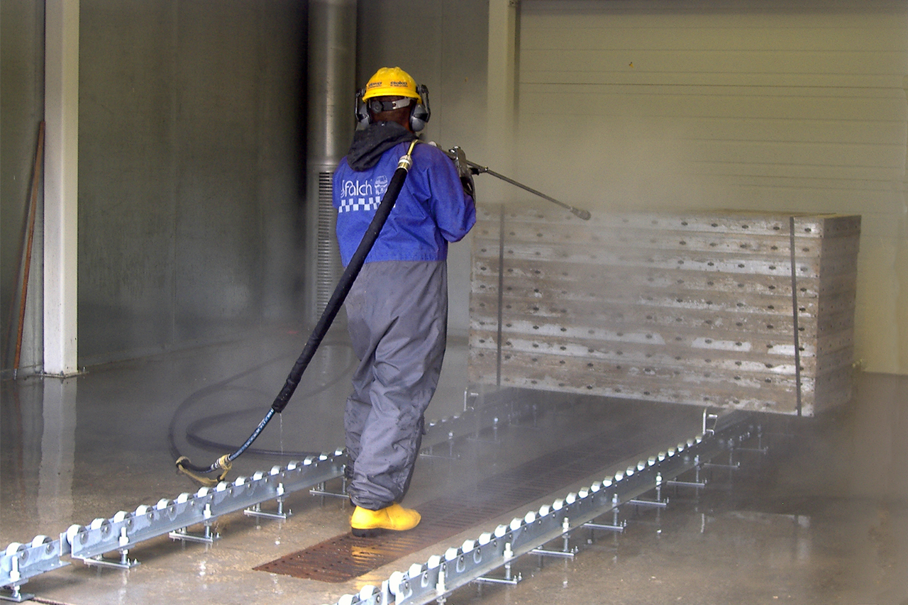 Person using Concrete Form Wash to wash large block of concrete on rails