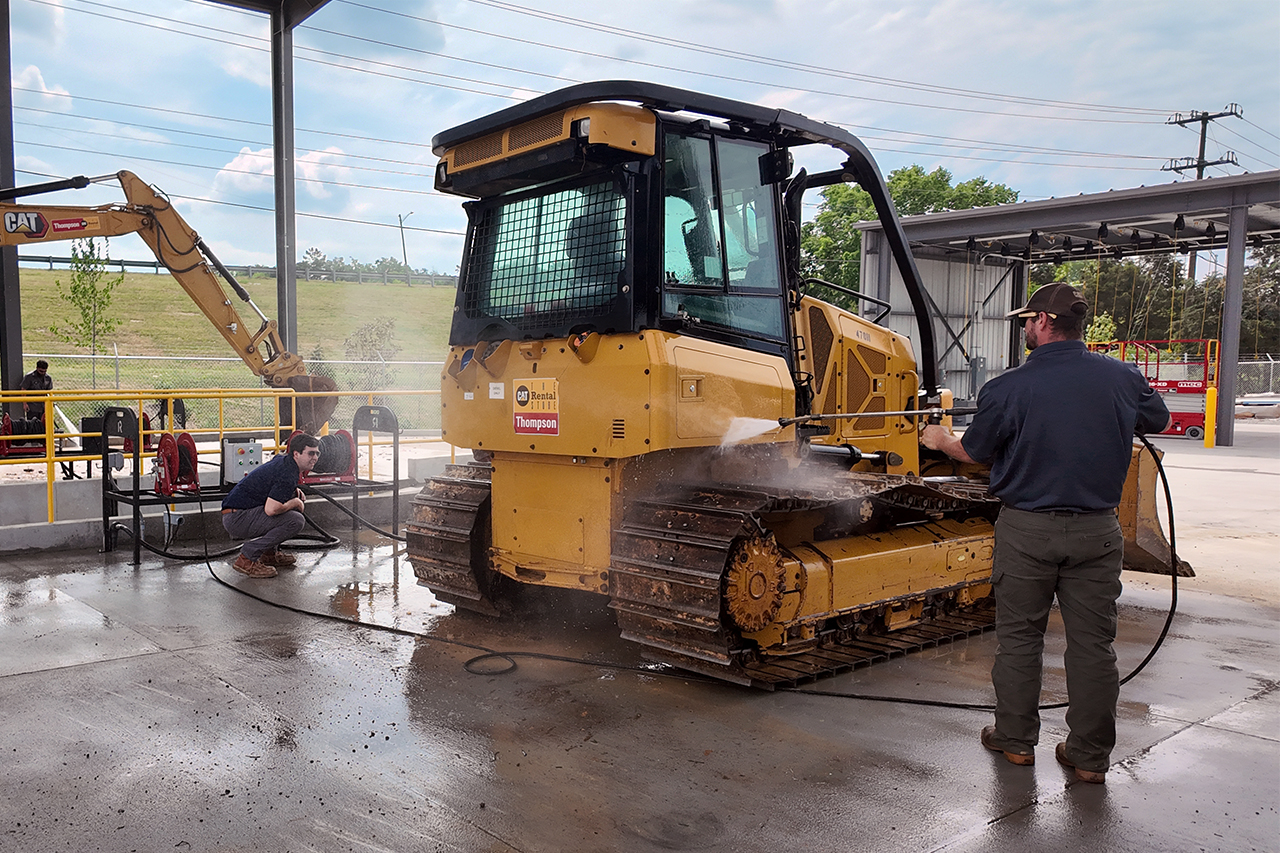 Person using Pressure Washer on Large Rental Equipment in Dual In-Ground Cement Wash Pad