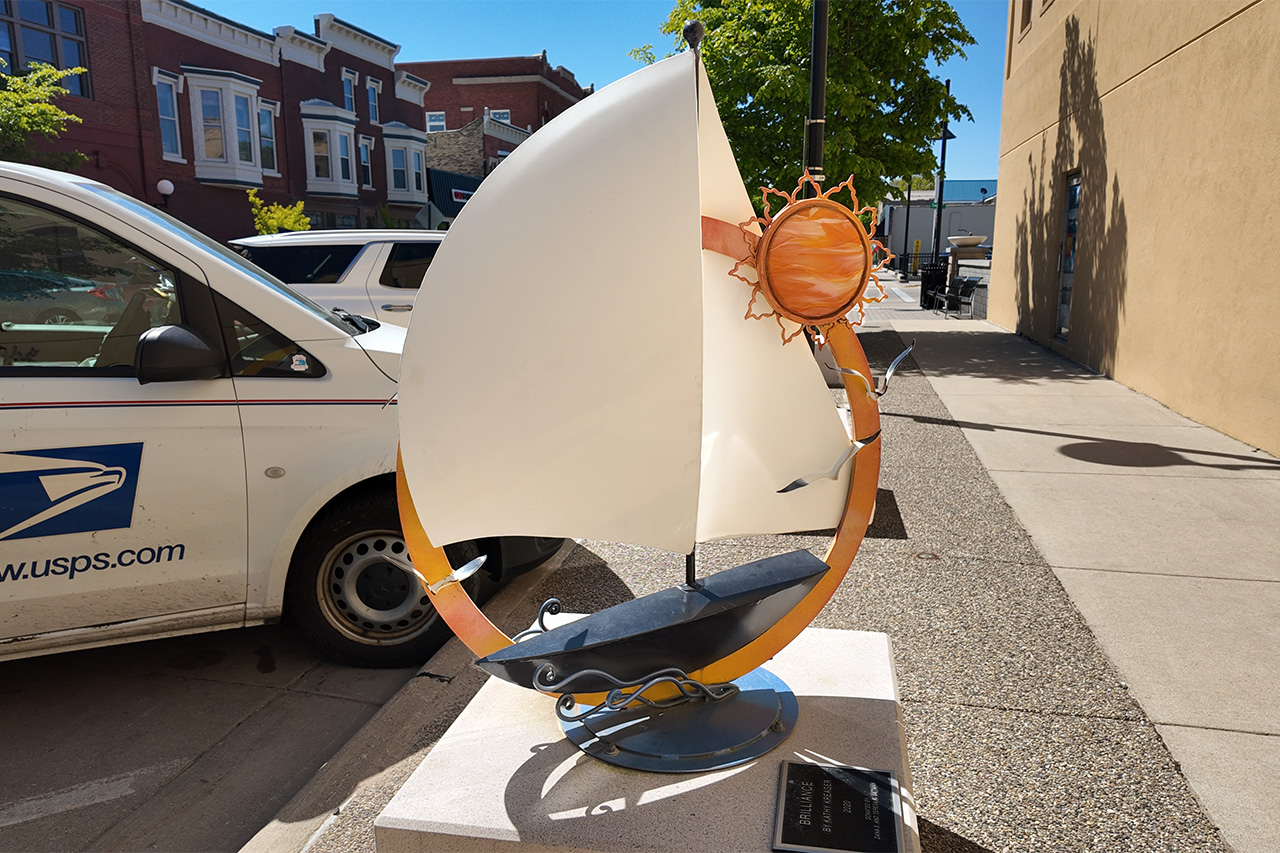 Brilliance By Kathy Kreager Brilliance By Kathy Kreager Sculpture depicts a sailboat with a sun, seagulls, and waves. Powder Coated By Riveer.