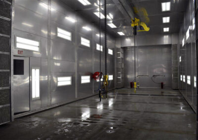 Manual Pretreatment Booth Interior, Stainless Steel room with embedded lights, diamond tread floor, and multiple manual spray wands.